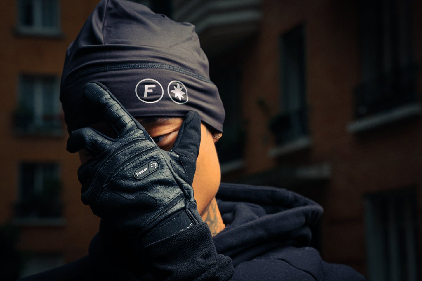 Homme cachant son visage avec Finesse Leather Gloves, portant aussi le 2-Shots Beanie.
