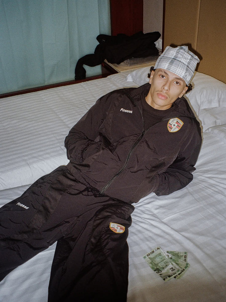 Model wearing the 911 tracksuit in black with the Tartan Skull Beanie - Finesse lookbook
