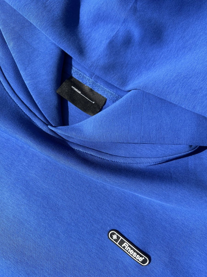 Zoom sur étiquette et patch du Finesse Air Cotton Hoodie bleu.