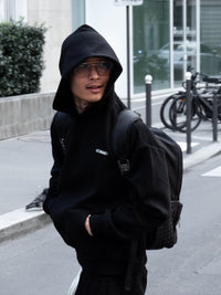 Mannequin en hoodie noir Finesse Air Cotton, capuche relevée, riant.