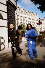 Un homme en Air Cotton noir et une femme en Air Cotton bleu courant dans une rue.