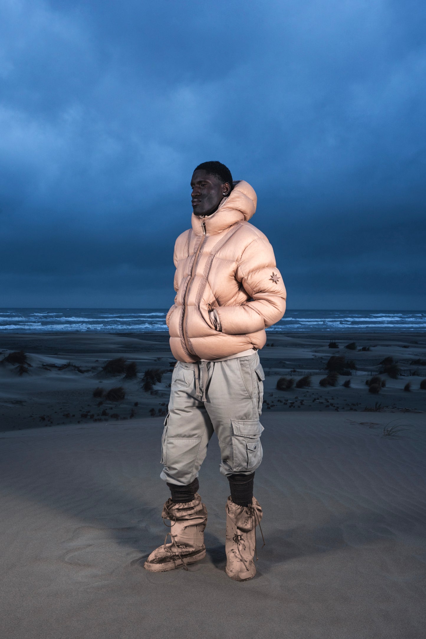 Homme de face dans les dunes au crépuscule en Alive Puffer Jacket beige