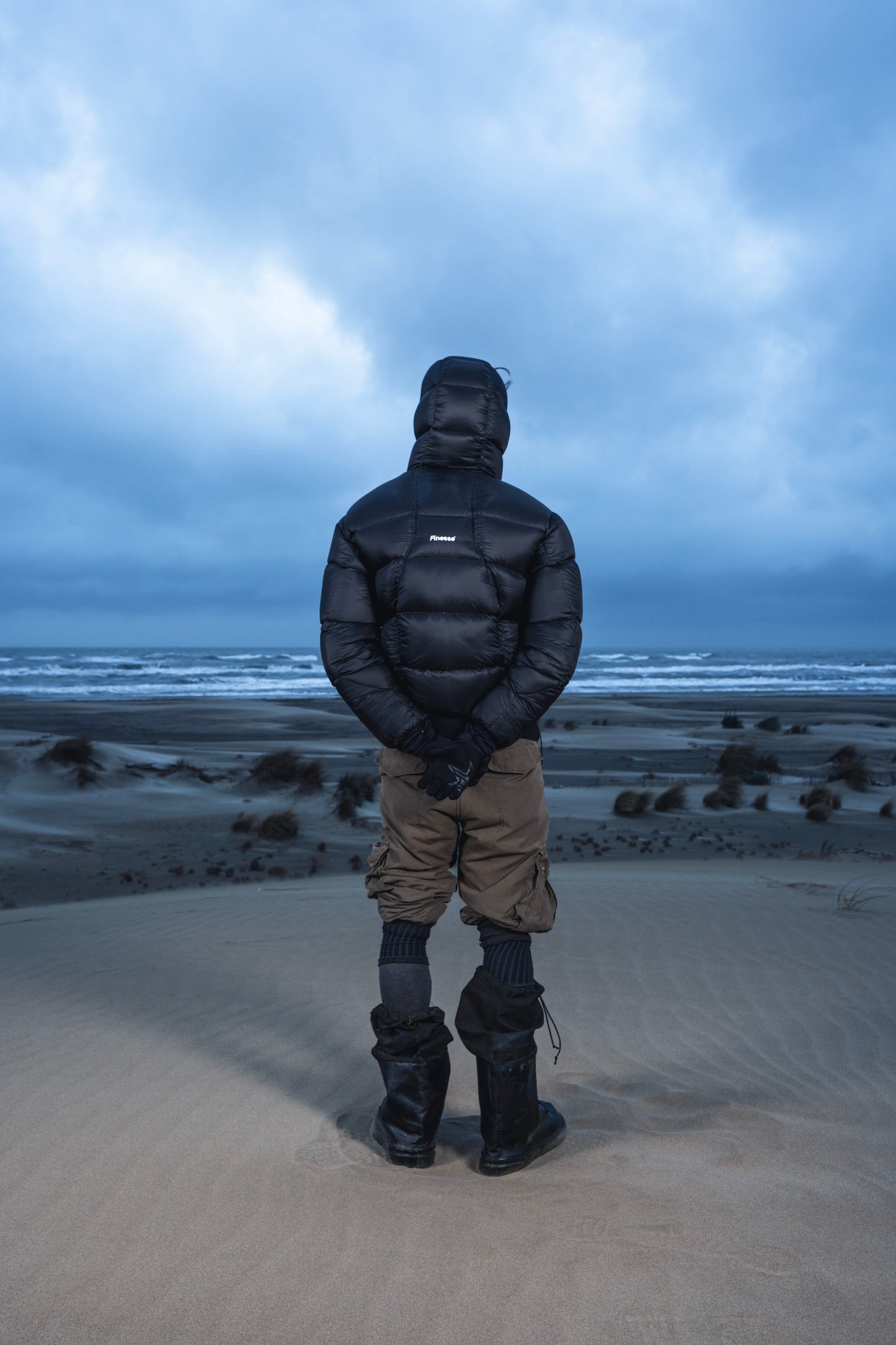 Homme de dos dans les dunes portant la Finesse Alive Puffer Jacket