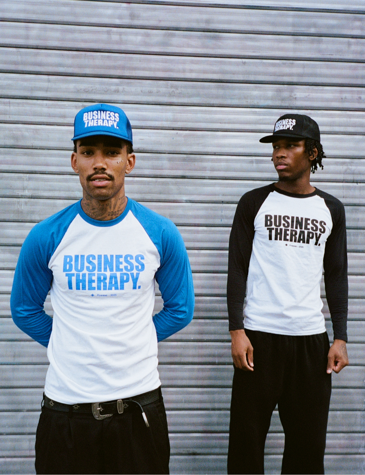 Deux hommes devant rideau métallique en Baseball Tee Business Therapy (bleu & noir) avec casquettes assorties