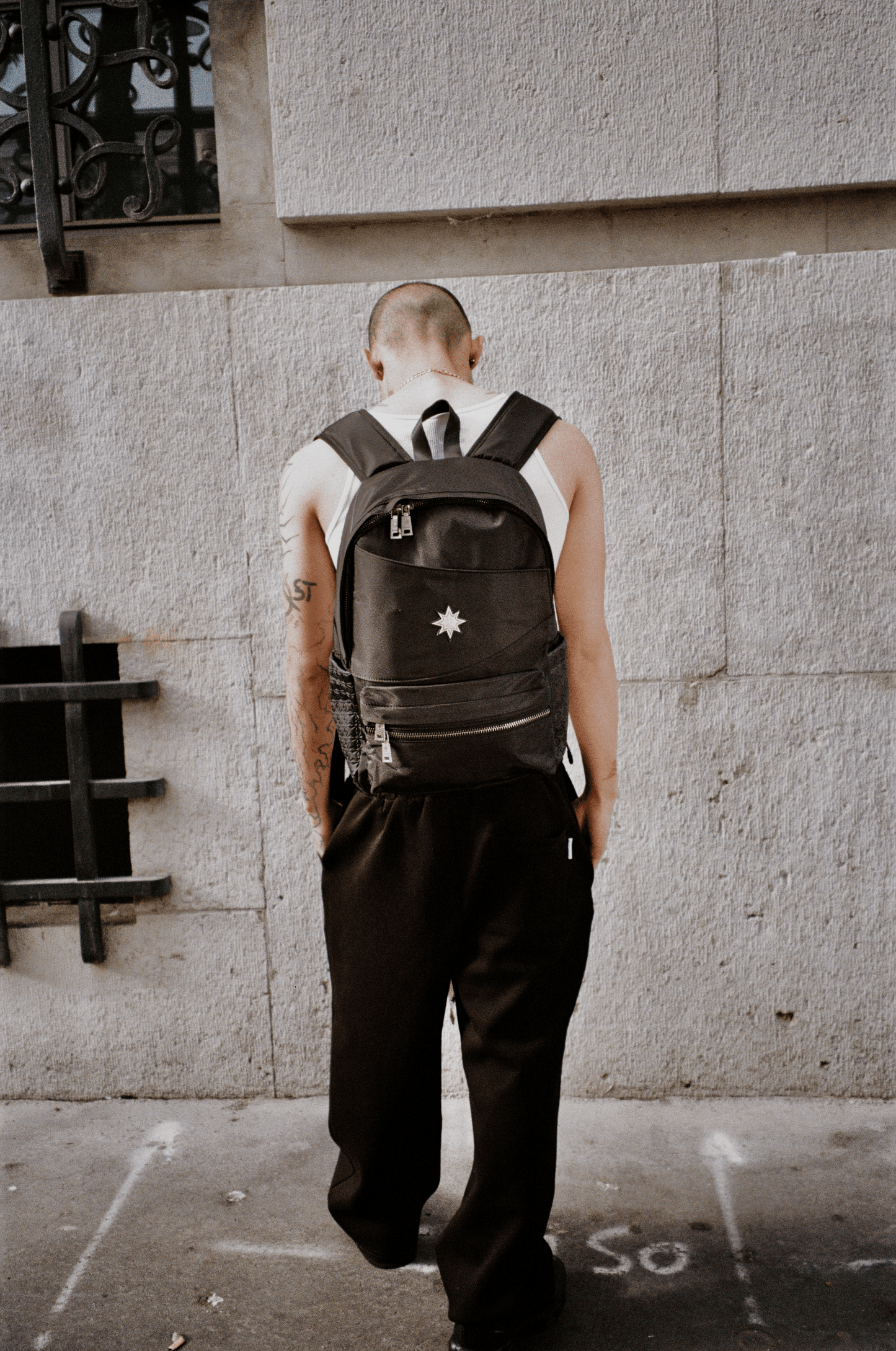 Homme vu de dos devant mur urbain portant le Finesse Black Vanta Backpack.