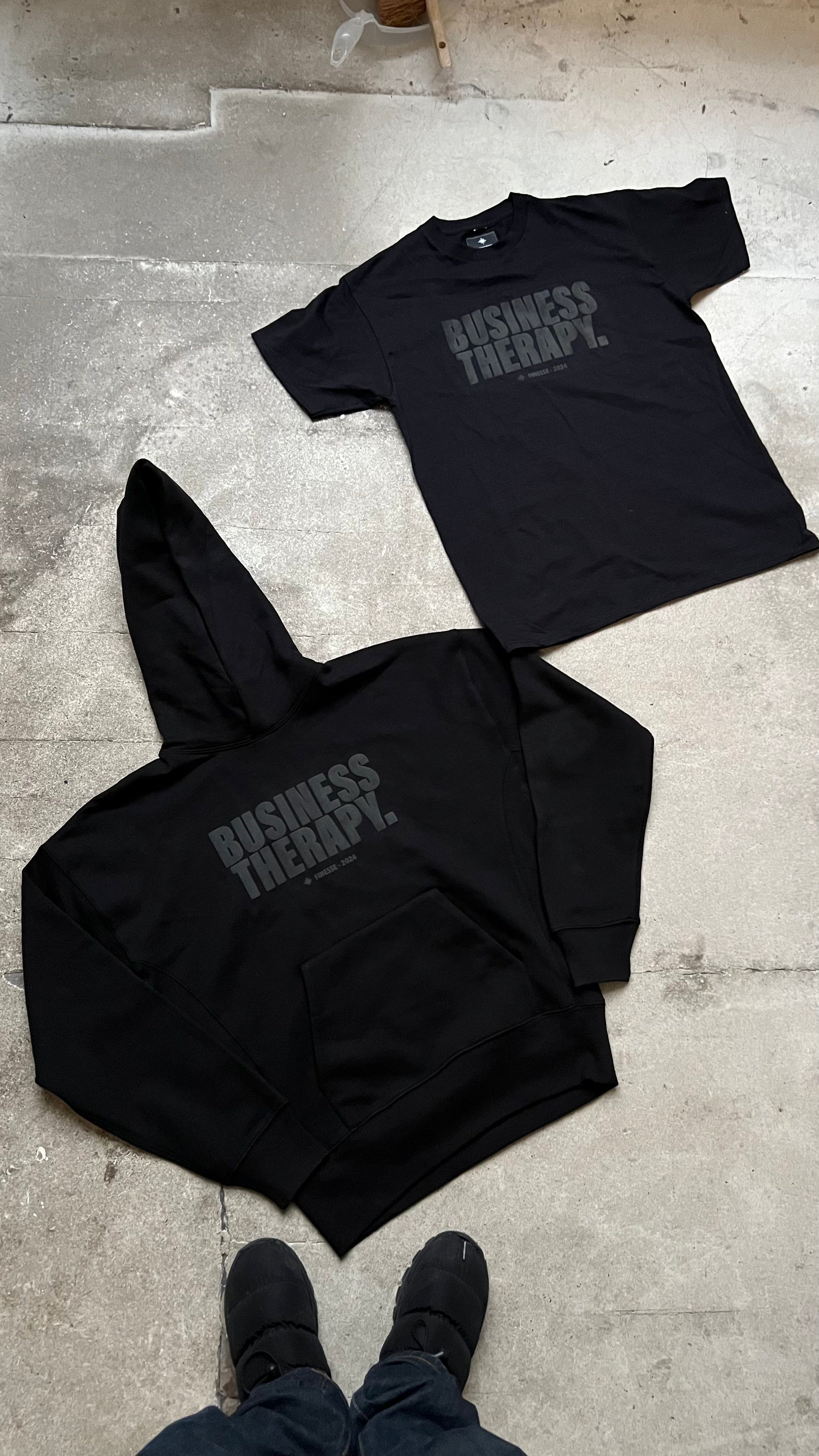 Hoodie et T-shirt Business Therapy Black on Black posés ensemble au sol