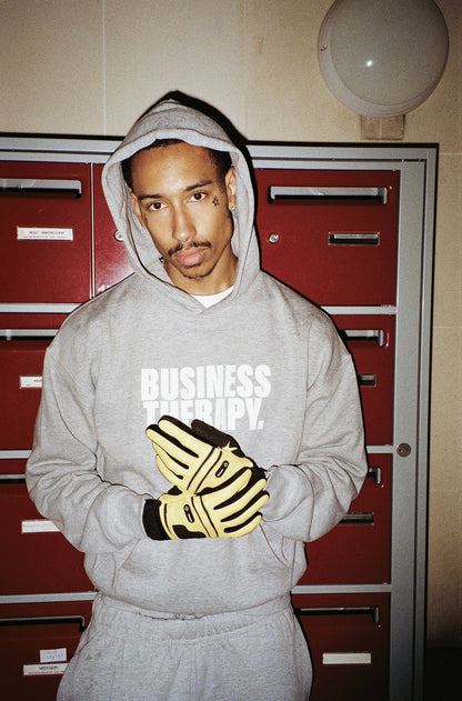 Homme en hoodie Business Therapy gris et gants Crocodile jaunes, dans cage d’escalier.