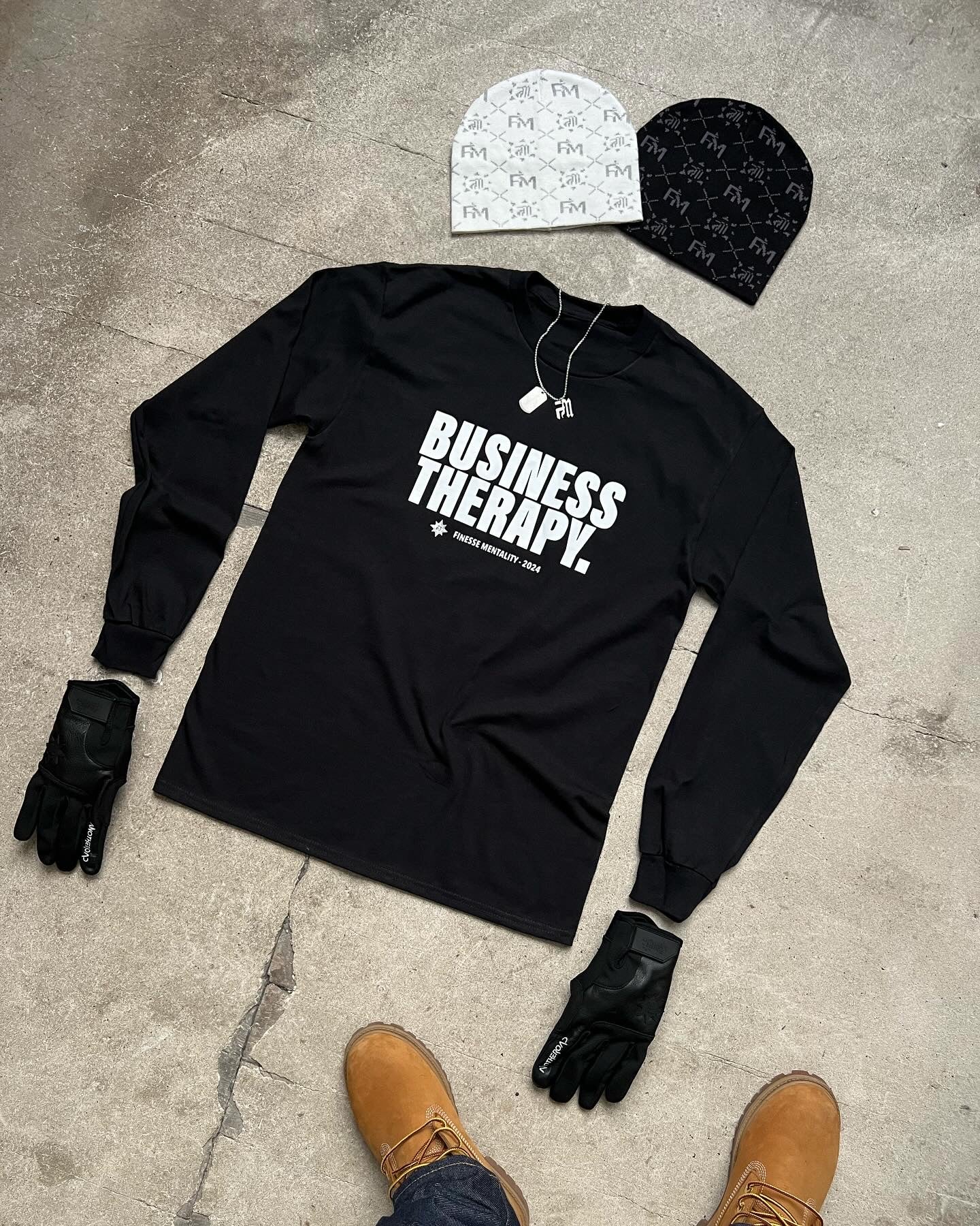 Packshot au sol en béton : t-shirt long-sleeve Business Therapy, gants Leather Gloves, chaîne Finesse Keychain et bonnets Snow et Black Earth2.