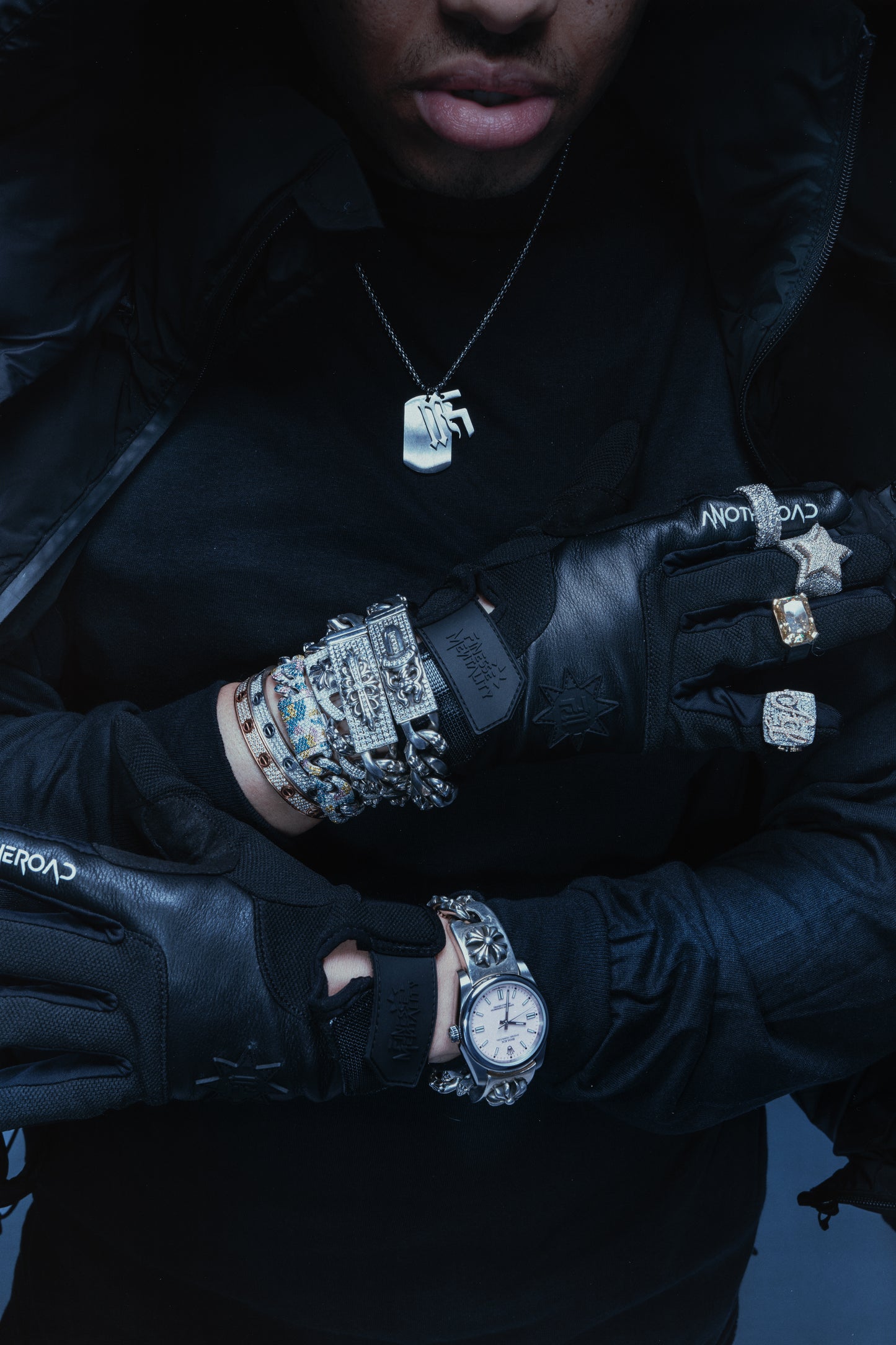 Gros plan sur les bras d’un homme portant la chaîne Finesse, gants, bagues et bijoux brillants VVS, montres et bracelets diamantés.