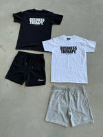 Variante de packshot au sol avec Cotton Shorts noir et gris, et T-shirts Business Therapy black et white.