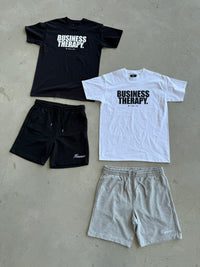 Packshot au sol avec Cotton Shorts noir et gris, associés aux T-shirts Business Therapy noir et blanc
