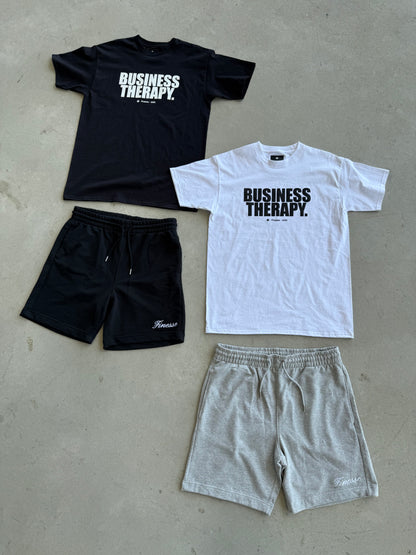 Variantes de packshot au sol avec Cotton Shorts noir et gris, et T-shirts Business Therapy noir et blanc.