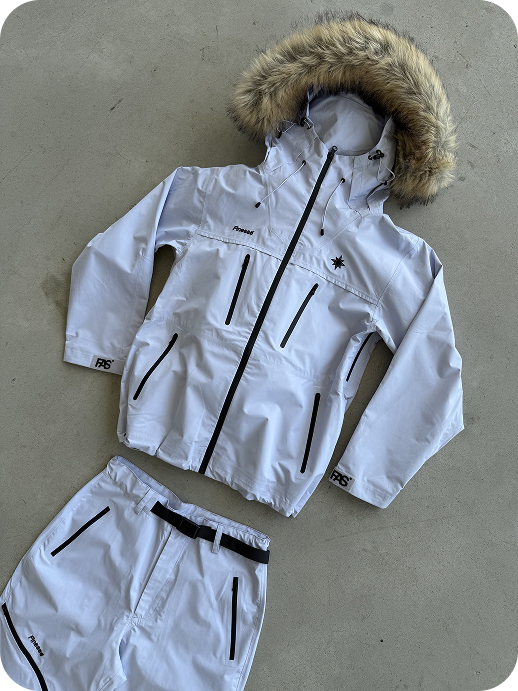 Hardshell blanche posée au sol avec aperçu du pantalon assorti.