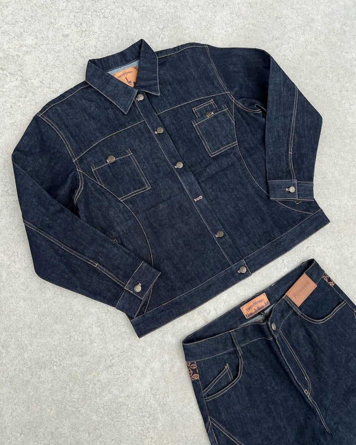 Ensemble FINESSE ADV DENIM SET posé sur sol en béton, focus sur la veste et ses détails.