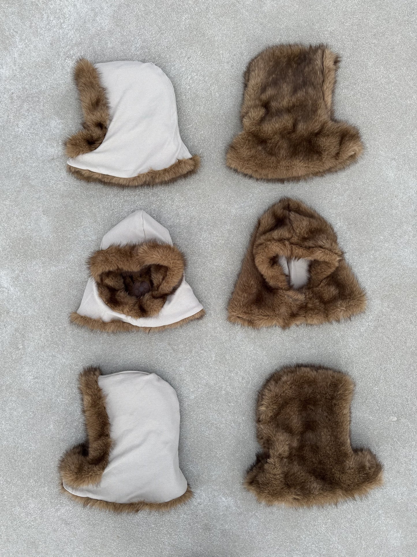 Six capuches FUR HOOD posées au sol, alignées en différentes positions