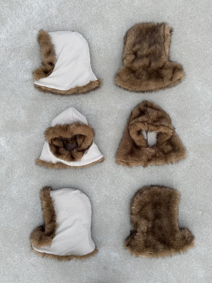 Six capuches FUR HOOD posées au sol, alignées en différentes positions