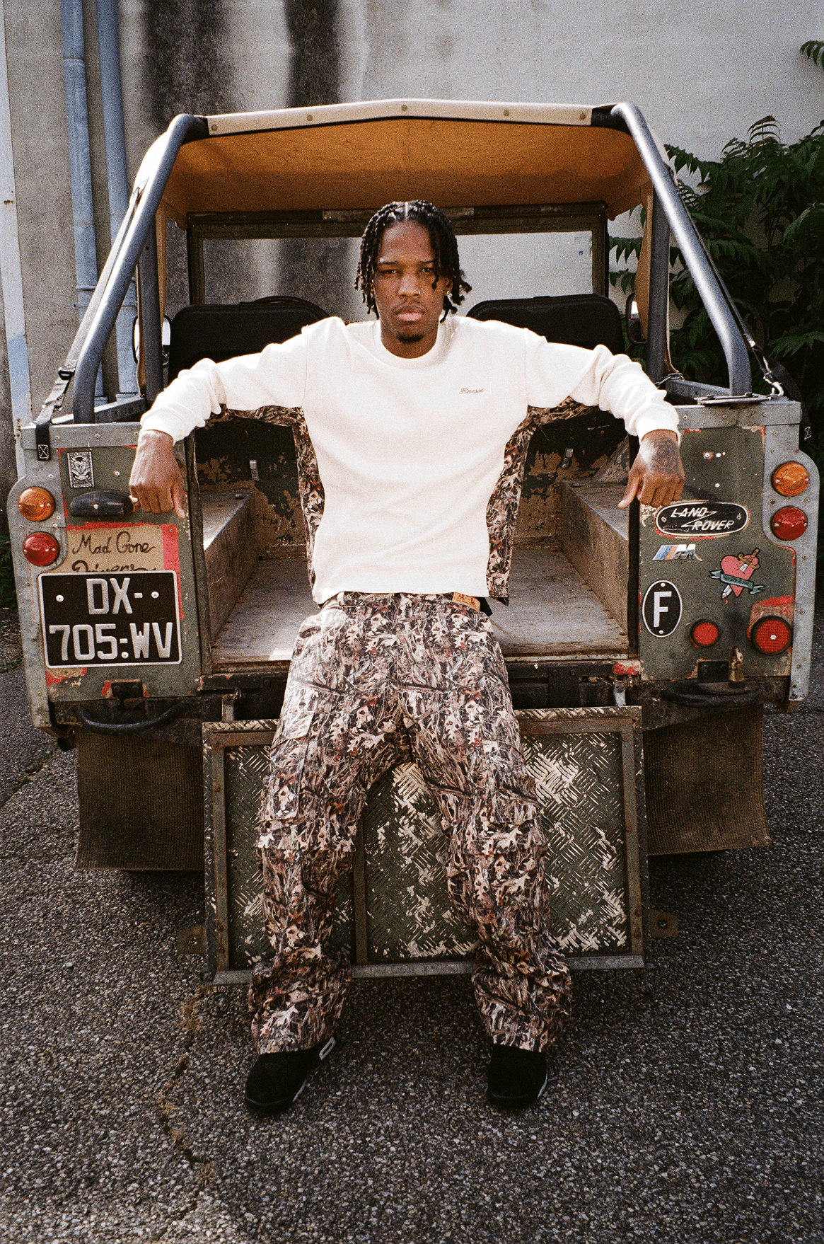 Homme appuyé sur le coffre du buggy, portant le Finesse 2-in-1 Cargo Pants-CAMO, look street décontracté.