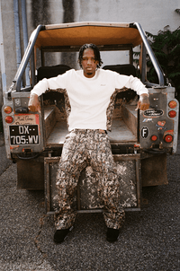 Homme appuyé sur le coffre du buggy, portant le Finesse 2-in-1 Cargo Pants-CAMO, look street décontracté.