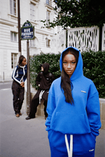 Scène rue Favard à Paris : trois personnes, femme en avant-plan avec capuche portant l’ensemble Air Cotton bleu."