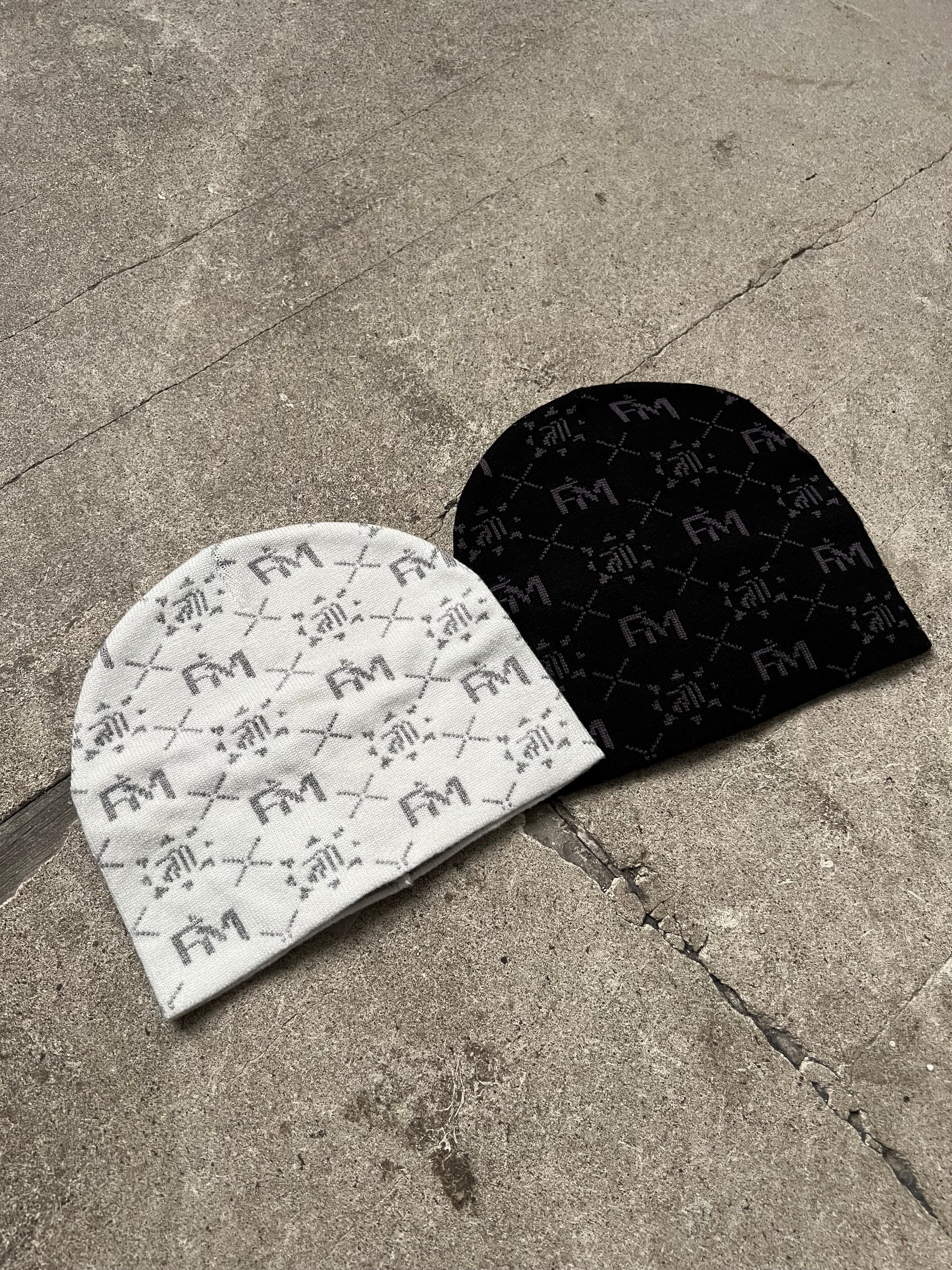 Bonnet Finesse Black Earth et bonnet Finesse Snow posés au sol en béton.