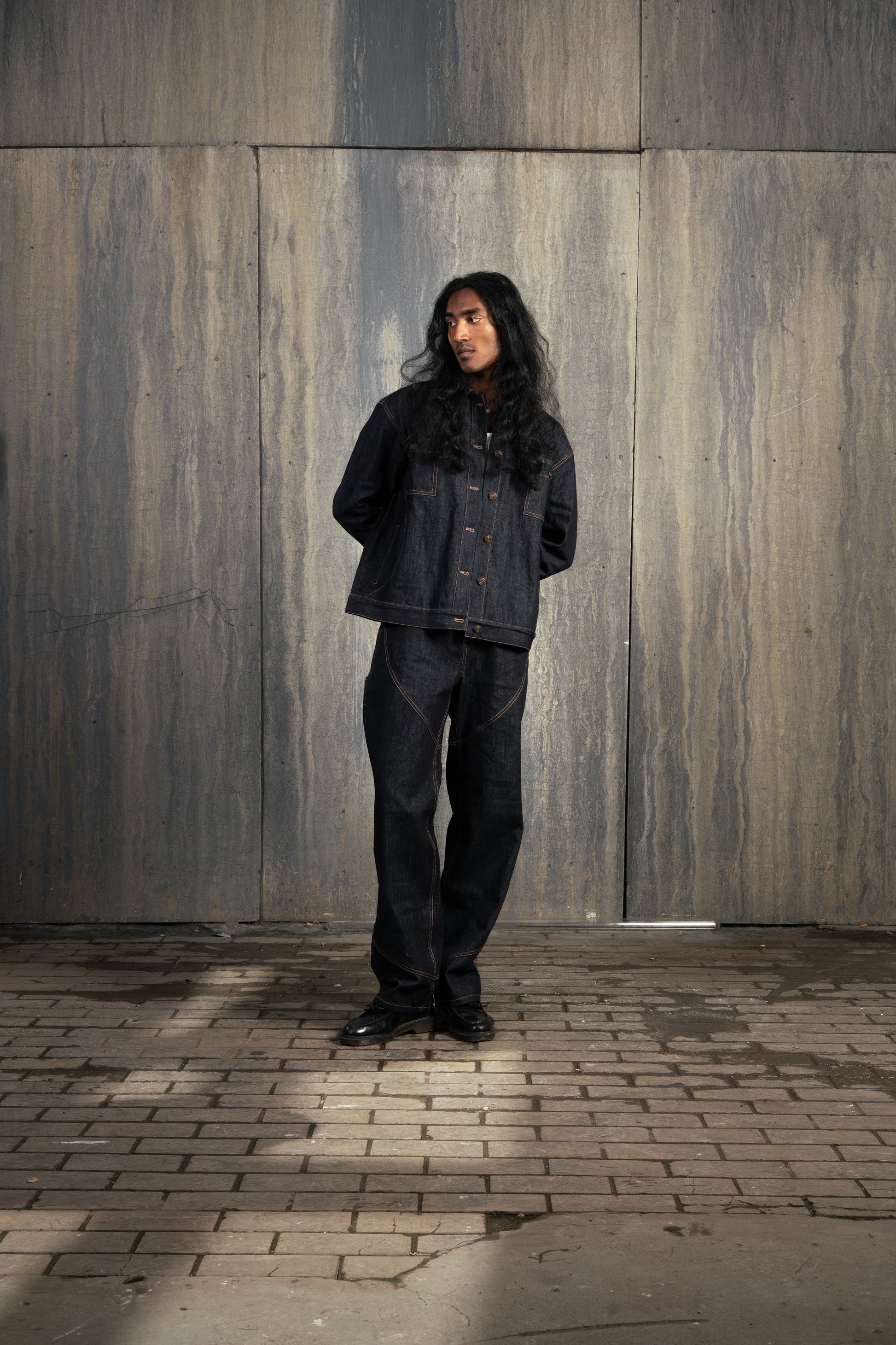 Homme de face en studio à décor industriel, bras derrière le dos, portant l’ensemble Finesse Denim Set ADV numéro 2