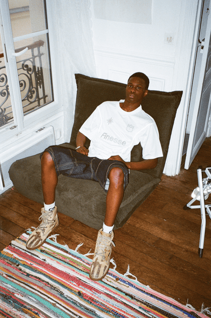 Homme assis affalé dans un pouf en Finesse Jersey Shirt noir et blanc, mannequin en premier plan en jersey blanc.