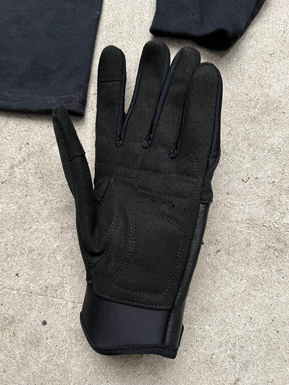 Packshot gros plan sur sol en béton d’un gant Finesse Leather Gloves en cuir, avec un long-sleeve flou en arrière-plan 2.