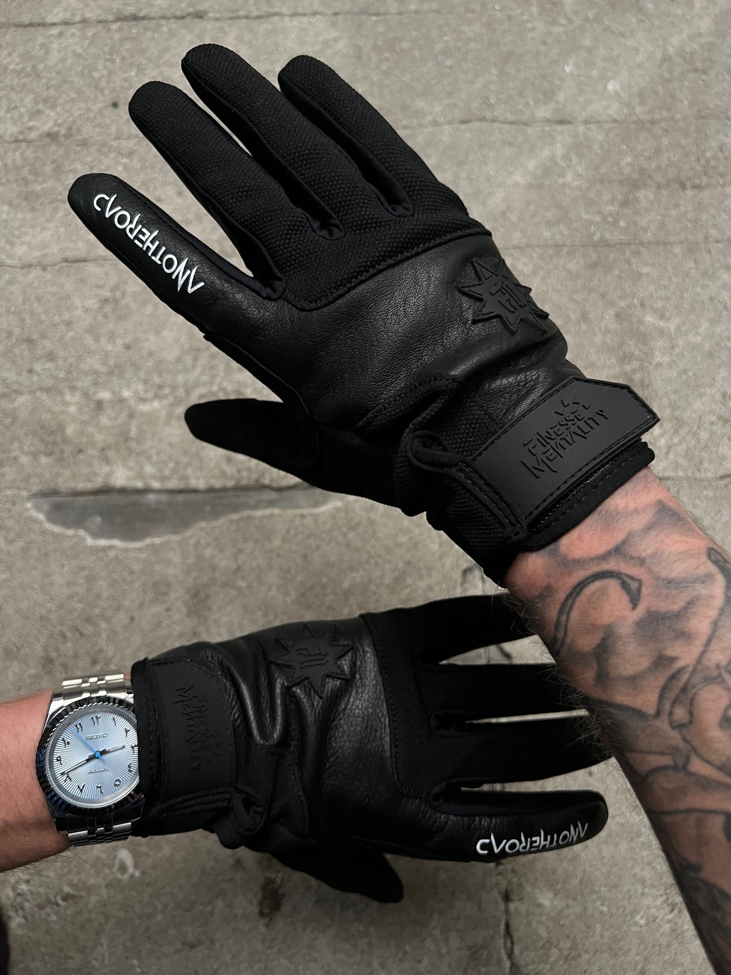 Photo d’un homme aux bras tatoués portant les gants Finesse Leather Gloves et une petite montre.