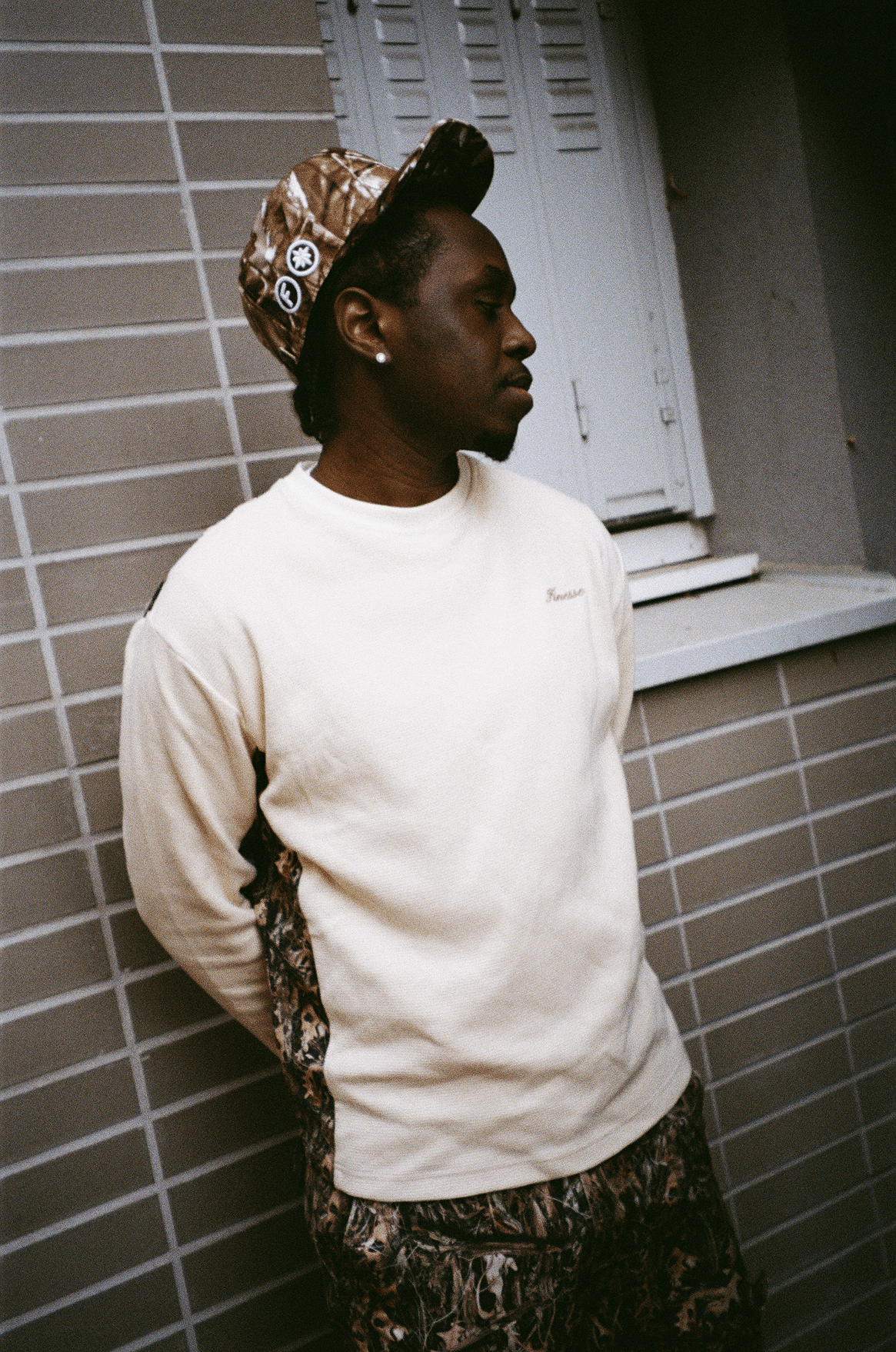 Zoom sur le rappeur 15 KAINZ en Finesse Military Top-Camo et "SIGN" Cap-CAMO, look street concentré.