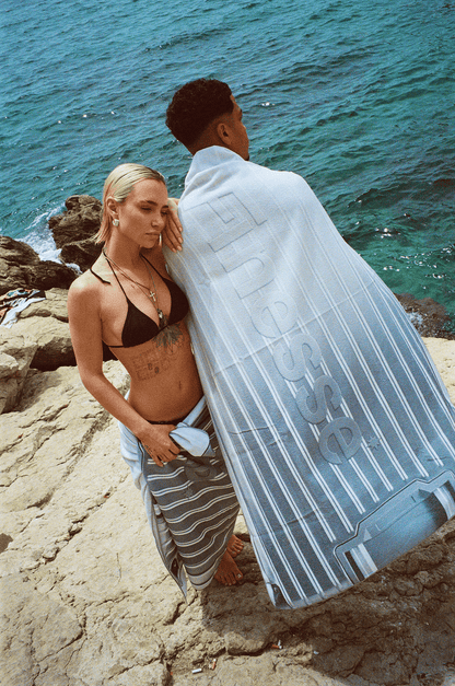 Femme de face et homme de dos dans les calanques, portant la serviette Finesse.