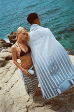 Femme de face et homme de dos dans les calanques, portant la serviette Finesse.