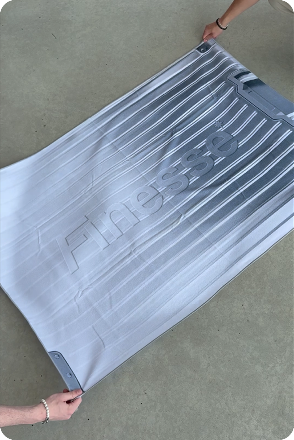 Serviette Finesse Towel tenue au-dessus du sol par quatre mains