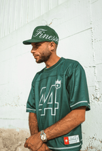 Homme en Jersey 44 green et Sign Cap, adossé à un mur sableux en lookbook urbain
