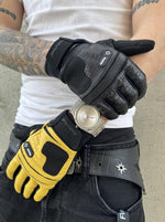 Homme tatoué, bras croisés, gant noir à droite et gant jaune à gauche