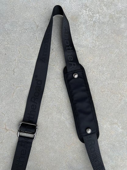 Sacoche Finesse Memorial Bag posée au sol, focus sur la lanière et ses détails