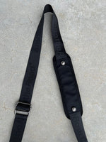 Sacoche Finesse Memorial Bag posée au sol, focus sur la lanière et ses détails