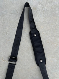 Sacoche Finesse Memorial Bag posée au sol, focus sur la lanière et ses détails