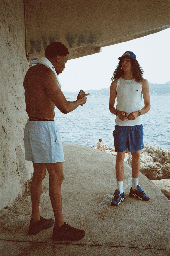 Deux hommes rient sous un rocher des calanques, en Swim Shorts et Tank Top