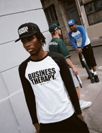 Homme en Trucker Cap noire Business Therapy au premier plan, deux hommes discutent derrière.