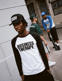 Homme en Trucker Cap noire Business Therapy au premier plan, deux hommes discutent derrière.